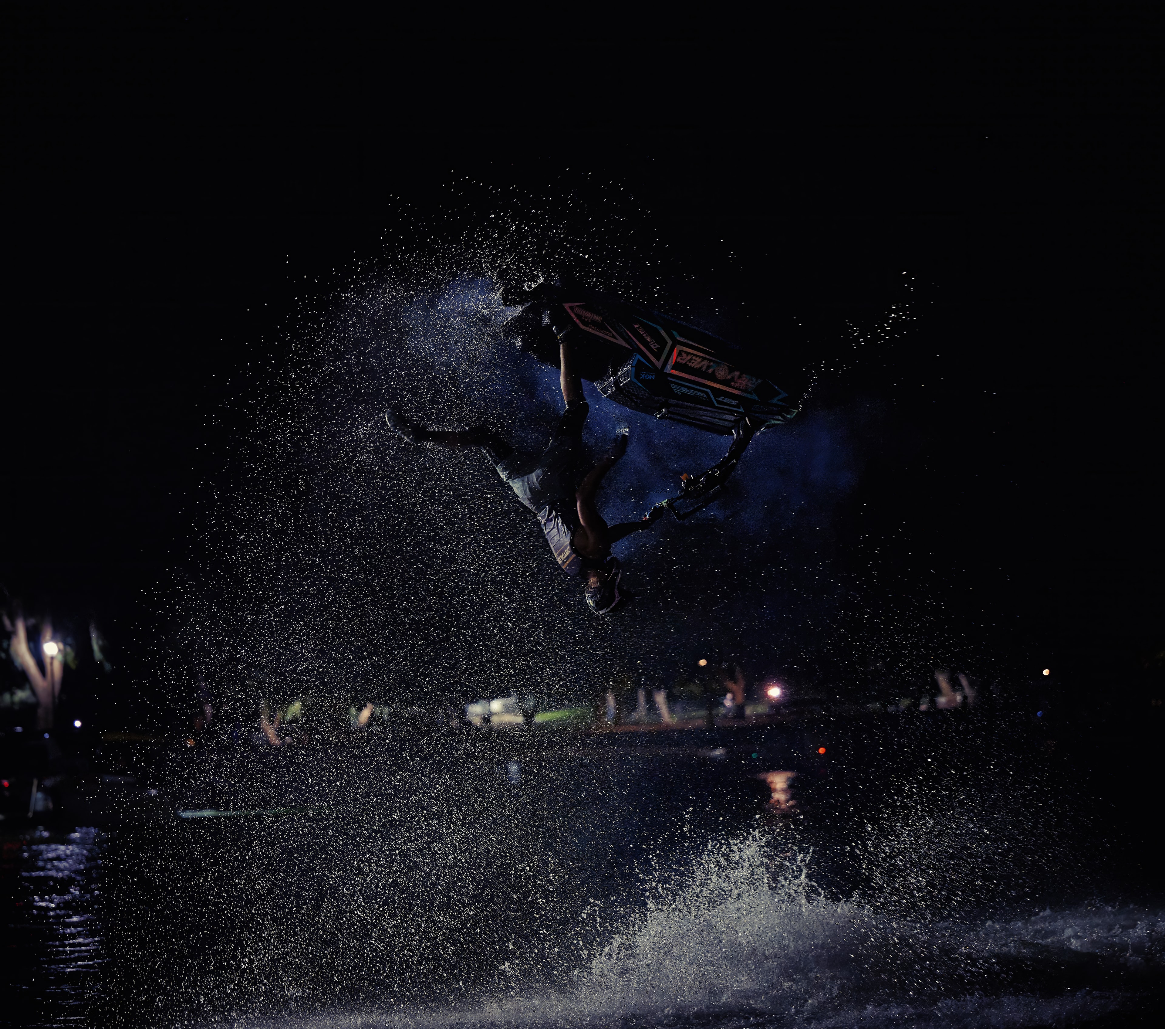 Action sports — jetski rider inverted mid-trick at night, water spray