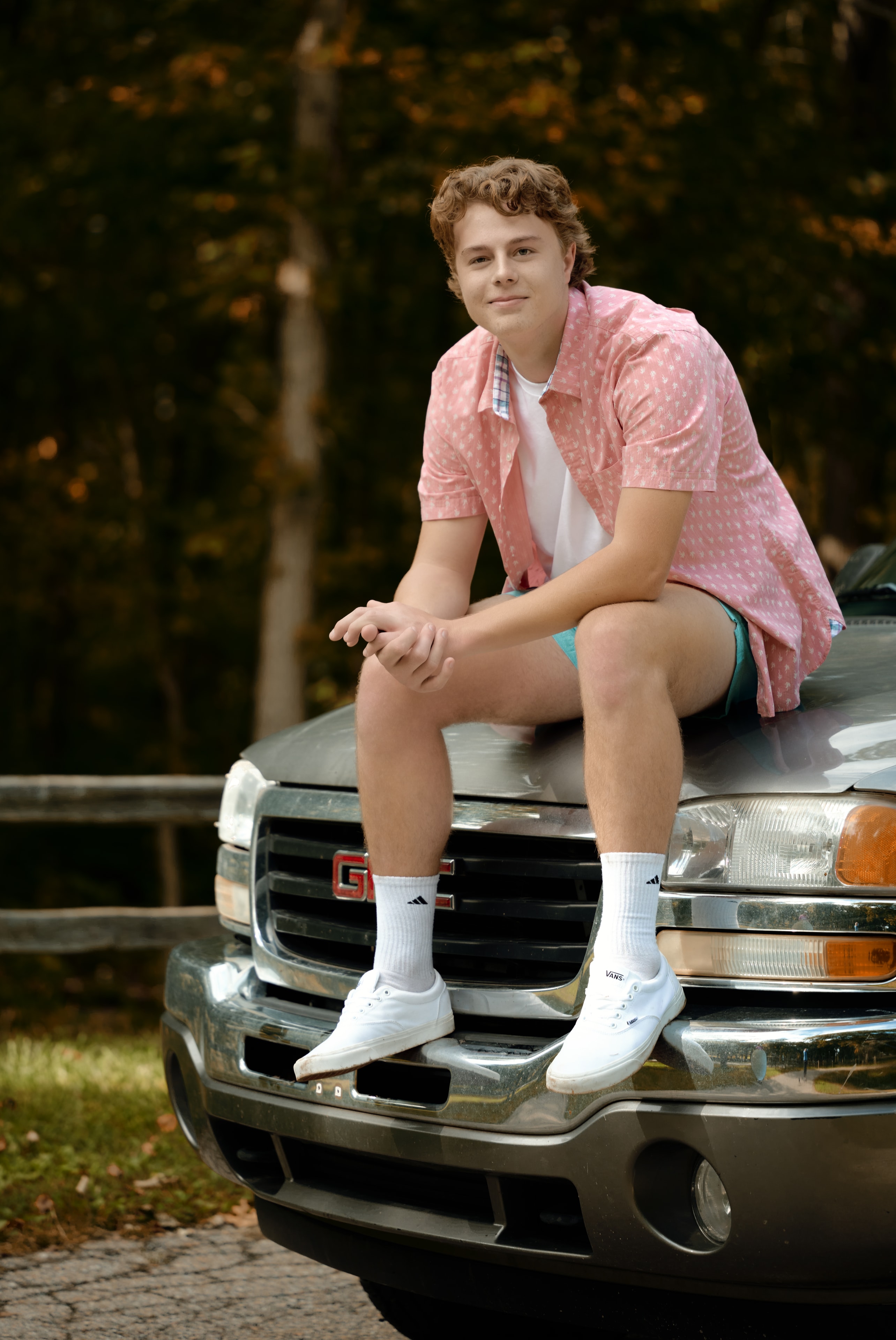Senior portrait — young man seated on truck hood, outdoor fall setting