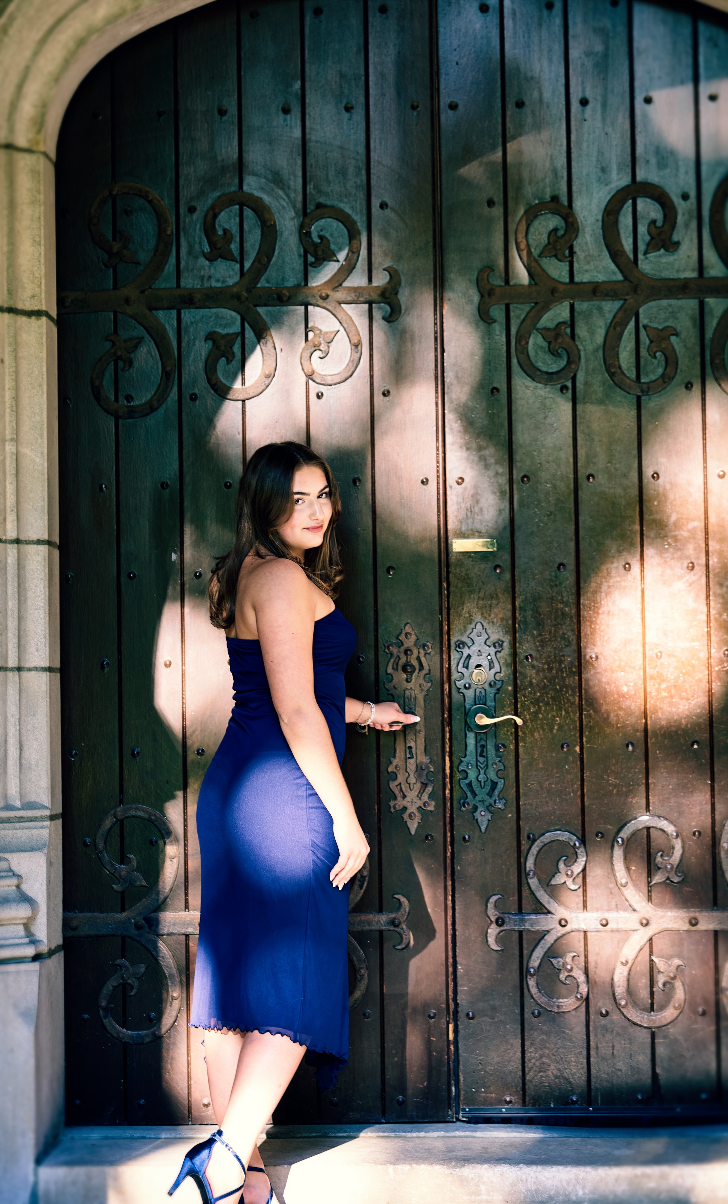 Senior portrait — young woman in blue dress posed against ornate green door